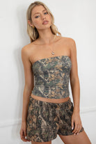 Woman wearing a camouflage strapless top and shorts against a white background