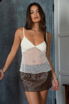 Woman wearing TIC TOC TL31345 SHANEA cream embroidered beaded mesh cami top with sequin detailing and adjustable straps with a pu leather brown skirt indoors.