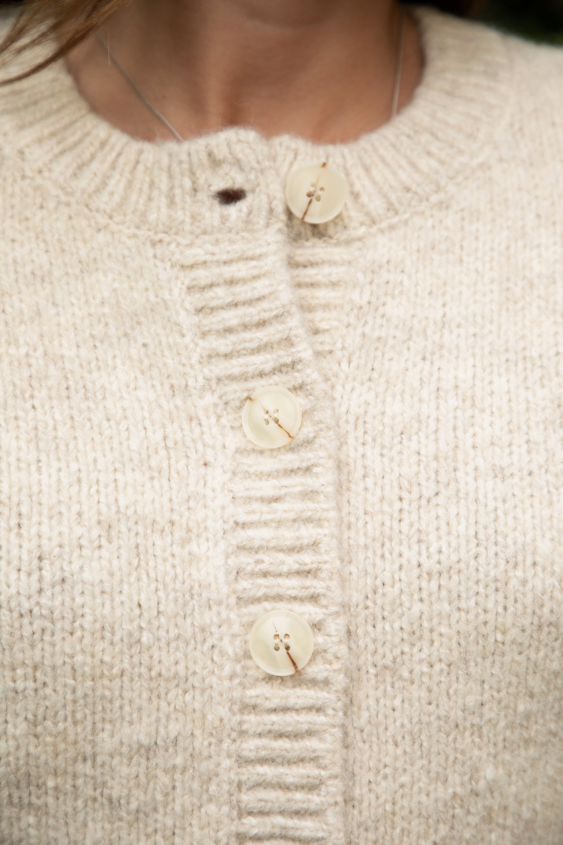 Close-up of a beige sweater with button details